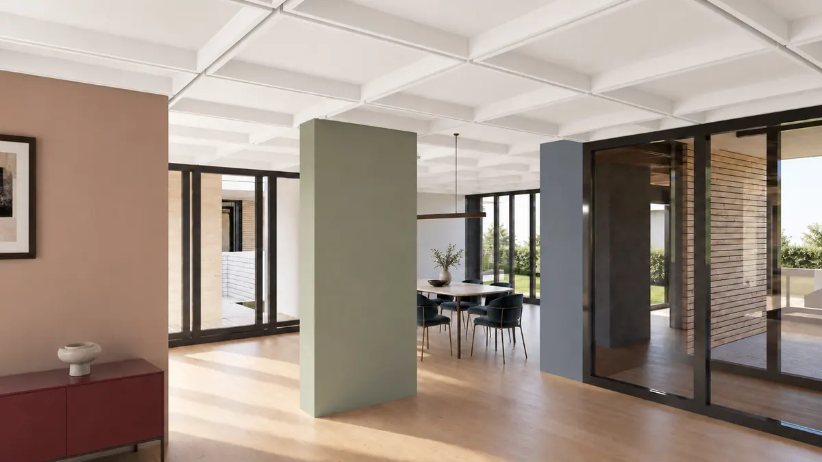Eine Wohnung auf einer Ebene: unter einer weissen Rippendecke gliedern farbige Wandscheiben — Terrakotta, Salbeigruen, Blaugrau — den durchgehenden Raum; in der Mitte ein Esstisch mit Stuehlen vor einer raumhohen Glaswand, rechts Glastueren zum Hof.